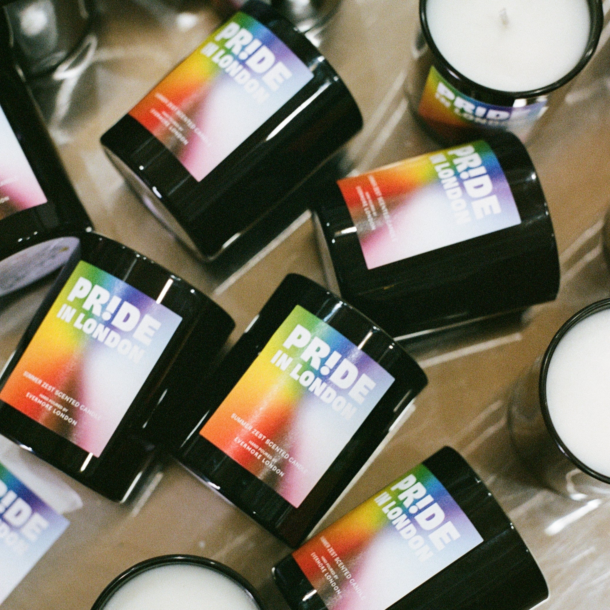Candle holders with Pride-themed labels on a reflective surface